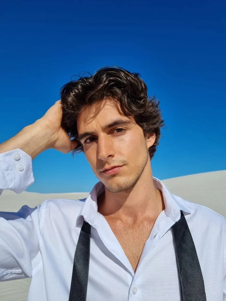 Outdoor portrait of Luca Bold in a white shirt against a blue sky